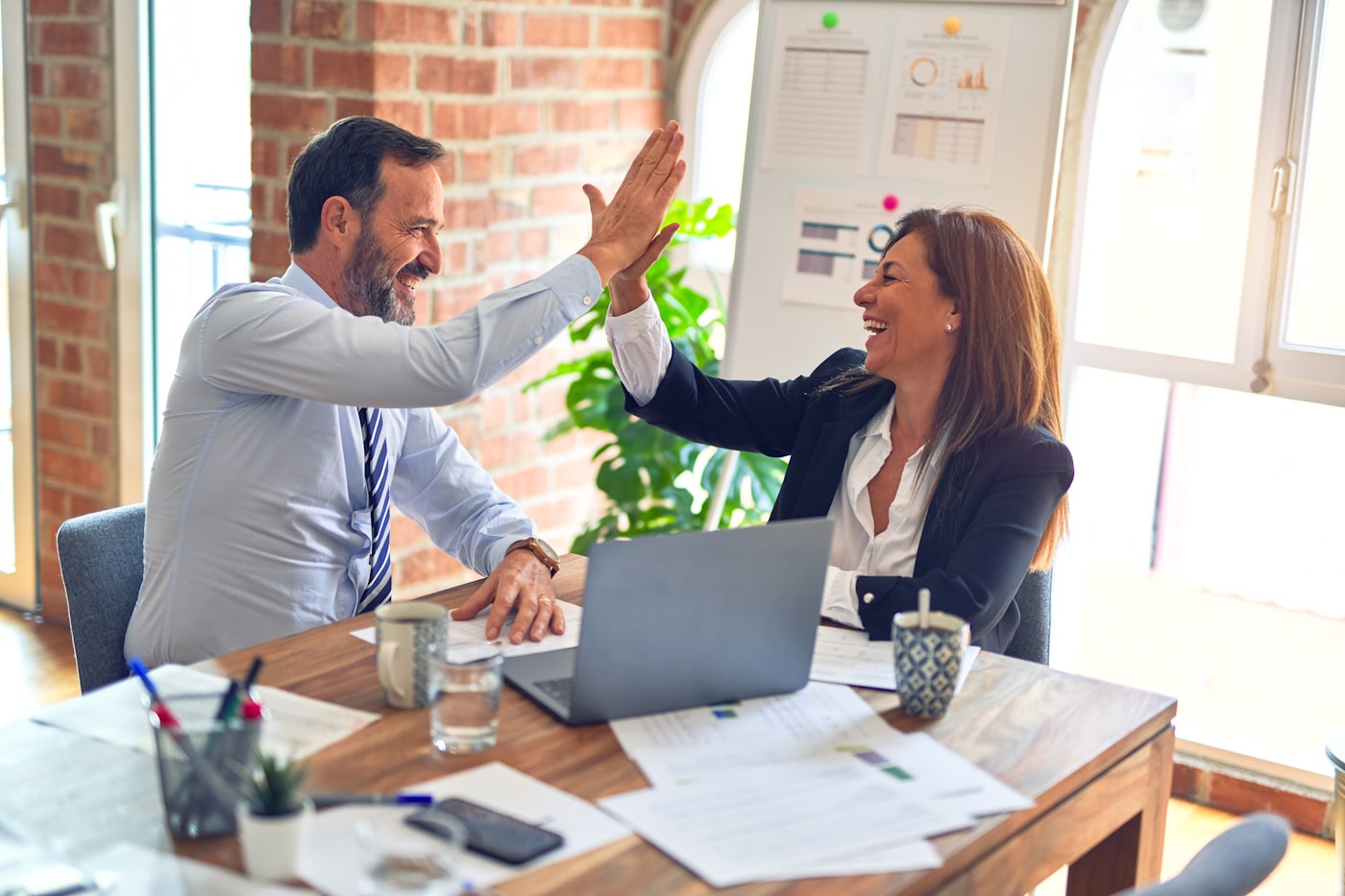 Two business partners celebrating at a desk